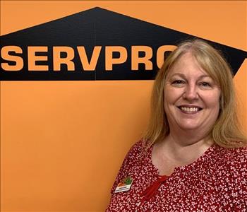 Female employee standing in front of SERVPRO wall, black polo 